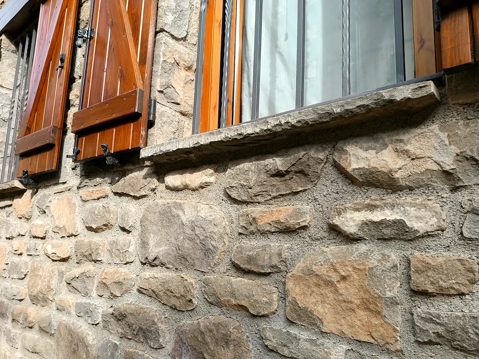 Ventana con contraventanas de madera sobre muro de piedra