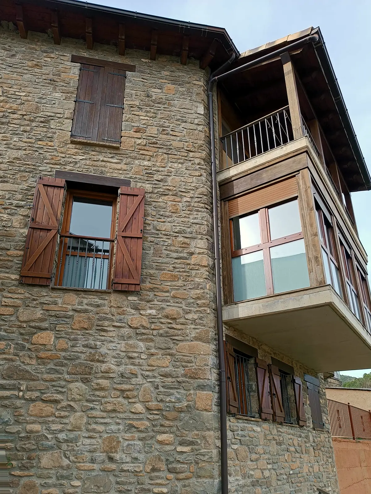 Esquina del edificio con mirador de madera y fachada de piedra