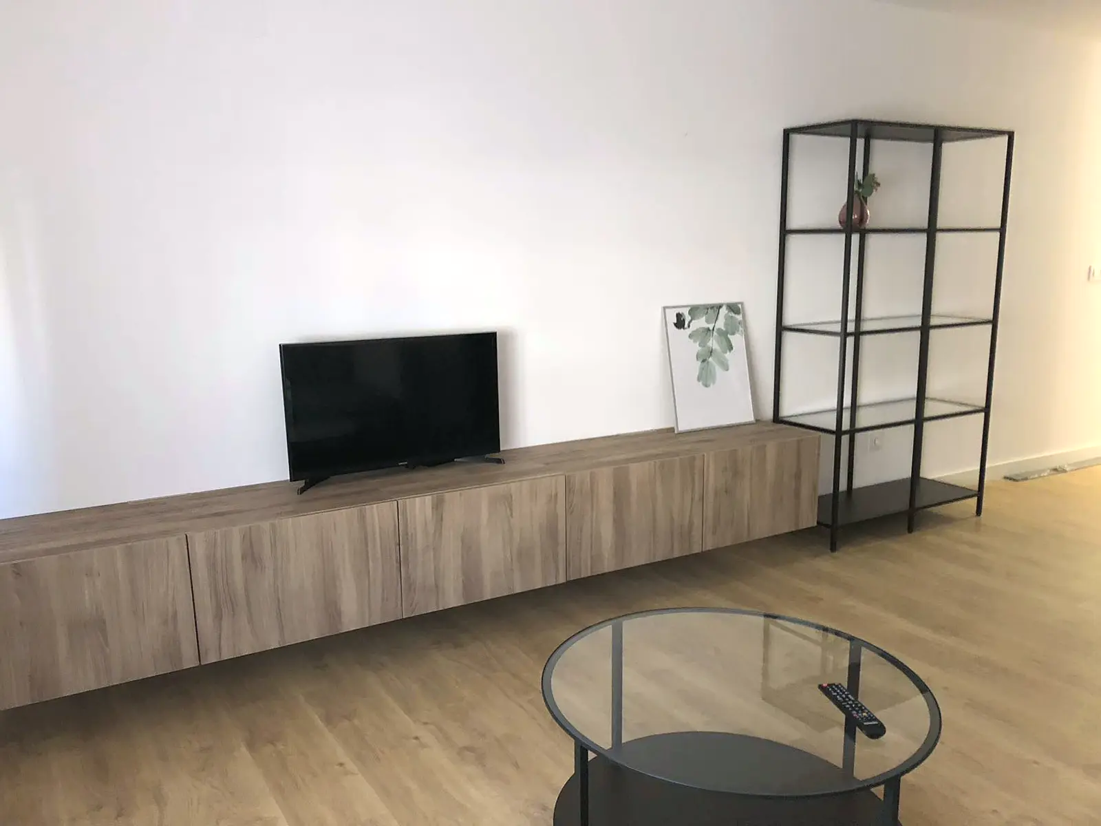 Salón con mueble de televisión suspendido y estantería negra