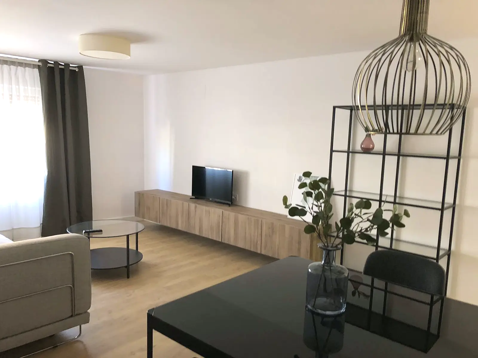 Salón hacia la ventana con cortinas y sofá gris